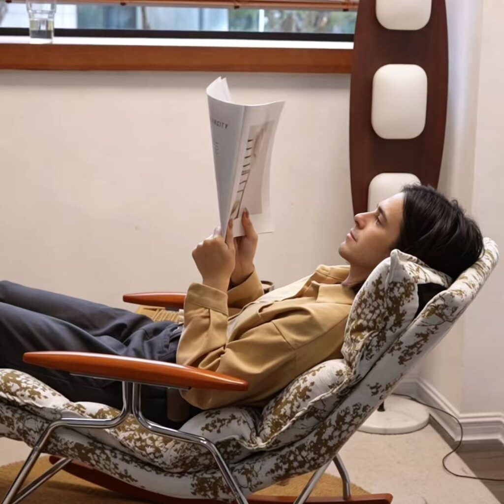 A man is lying in a comfortable chair, reading a book