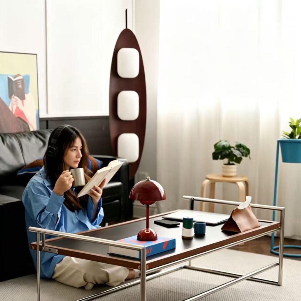 A woman sits cross-legged on the ground, drinking coffee and reading a book